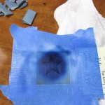 The mask for the star is aligned in the circle, and Insignia Blue is sprayed, again, going light in some areas.